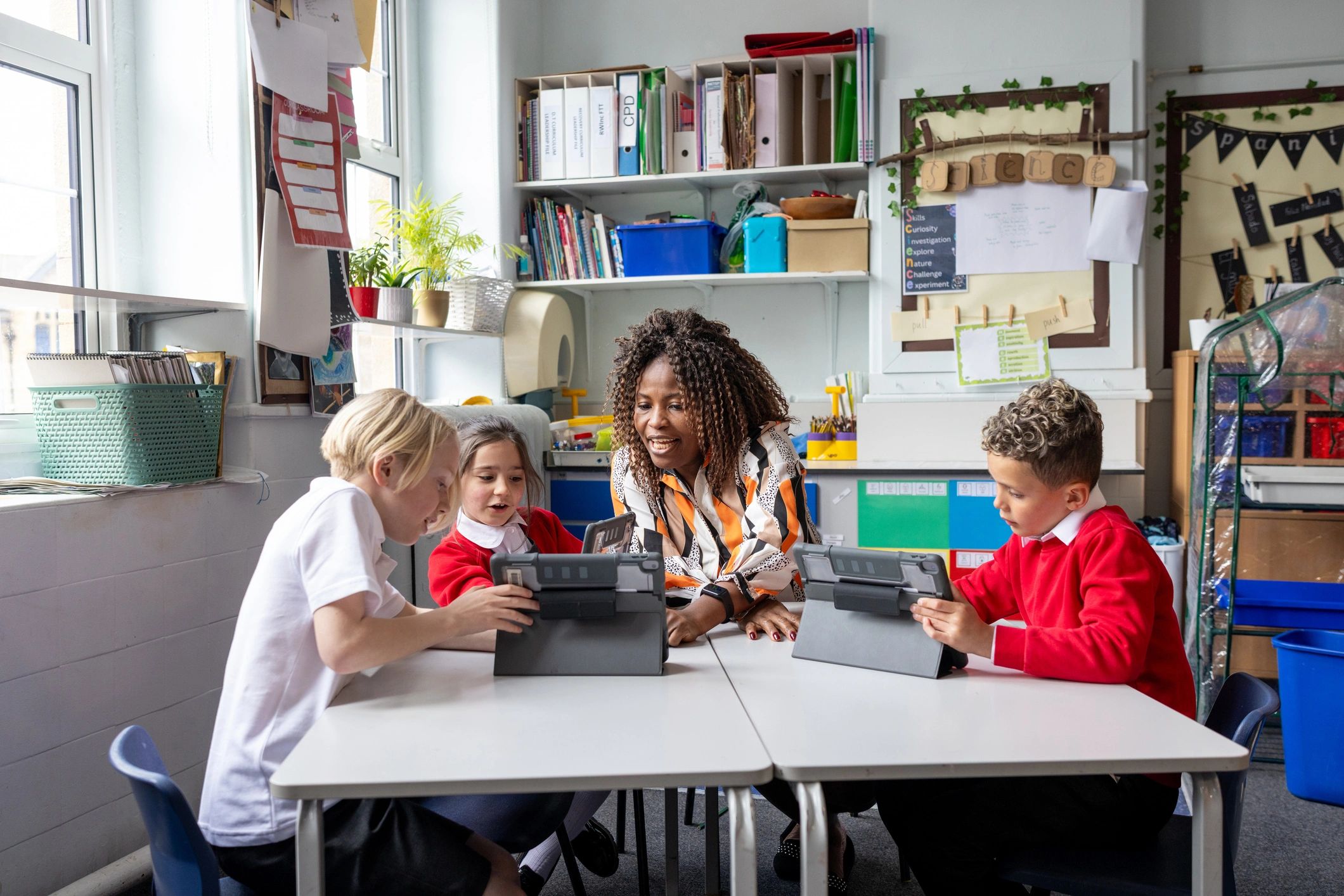 Teacher supporting students using tablets in a classroom